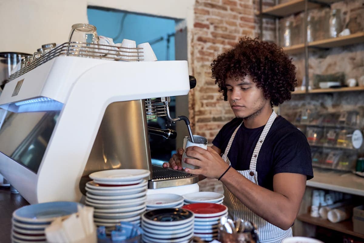 A barista steams milk at an espresso machine.